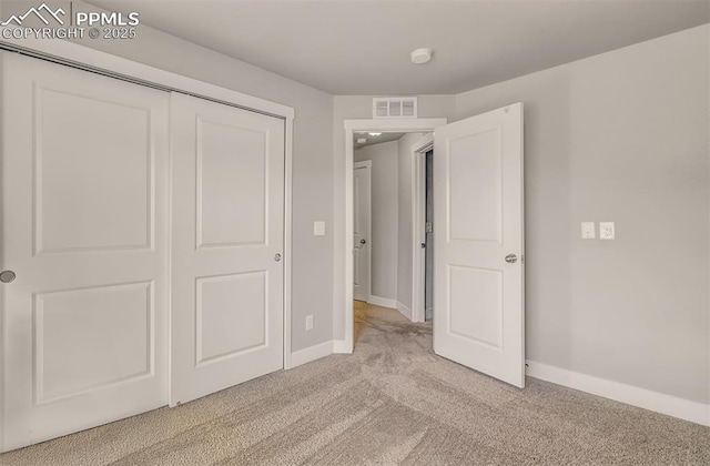 unfurnished bedroom featuring light carpet and a closet