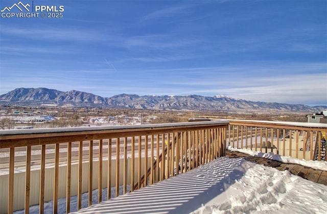 snow covered deck with a mountain view