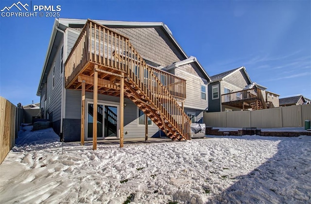 snow covered house with a wooden deck