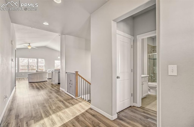 hallway with vaulted ceiling and light hardwood / wood-style flooring