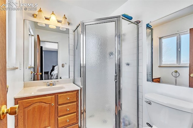 bathroom featuring a shower with door, vanity, and toilet