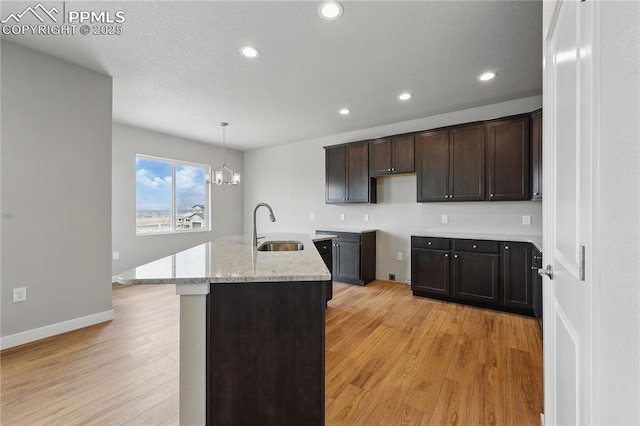 16896 Greenfield Dr, Monument, CO 80132 - kitchen with dark brown cabinets, light wood-style flooring, recessed lighting, and a sink