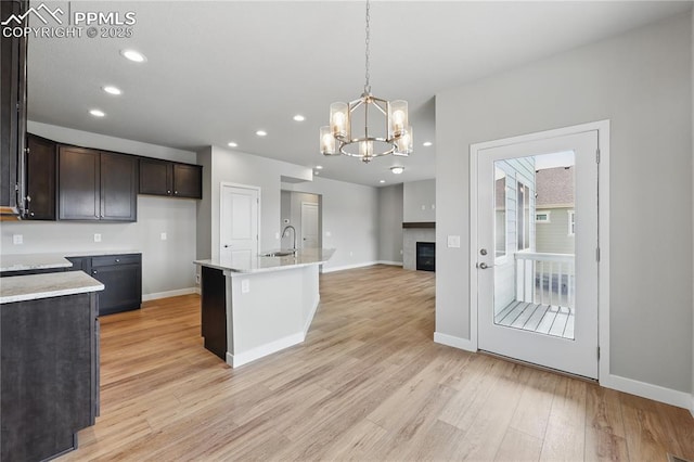 16896 Greenfield Dr, Monument, CO 80132 - kitchen featuring dark brown cabinetry, light countertops, a sink, baseboards, and light wood-type flooring