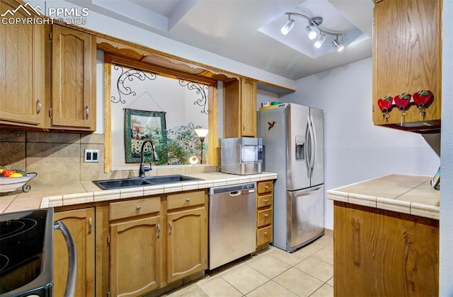 kitchen with sink, tile counters, decorative backsplash, and stainless steel appliances