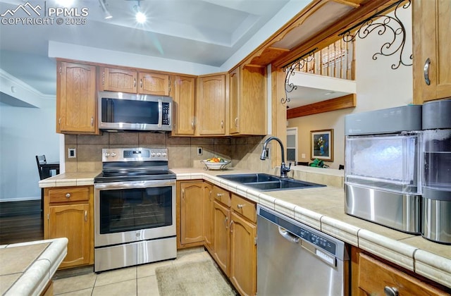 kitchen featuring sink, backsplash, stainless steel appliances, and tile countertops