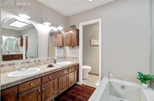 bathroom featuring hardwood / wood-style flooring, toilet, a skylight, vanity, and decorative backsplash