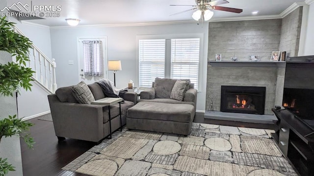 living room with a tile fireplace, dark hardwood / wood-style floors, ceiling fan, and ornamental molding