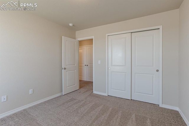 unfurnished bedroom with a closet and light colored carpet