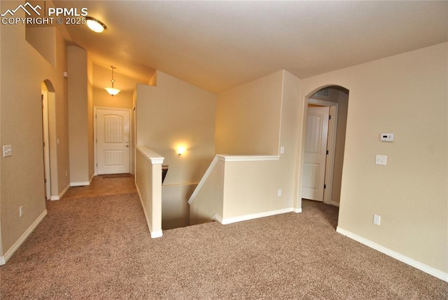 carpeted spare room featuring lofted ceiling