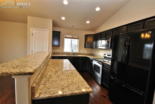 kitchen featuring vaulted ceiling, appliances with stainless steel finishes, sink, a center island, and light stone counters