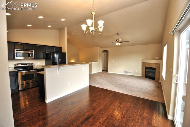 kitchen featuring a breakfast bar area, hanging light fixtures, stainless steel appliances, a center island, and light stone counters