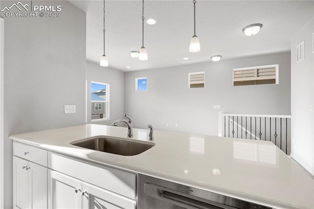 kitchen with hanging light fixtures, white cabinetry, sink, and dishwashing machine