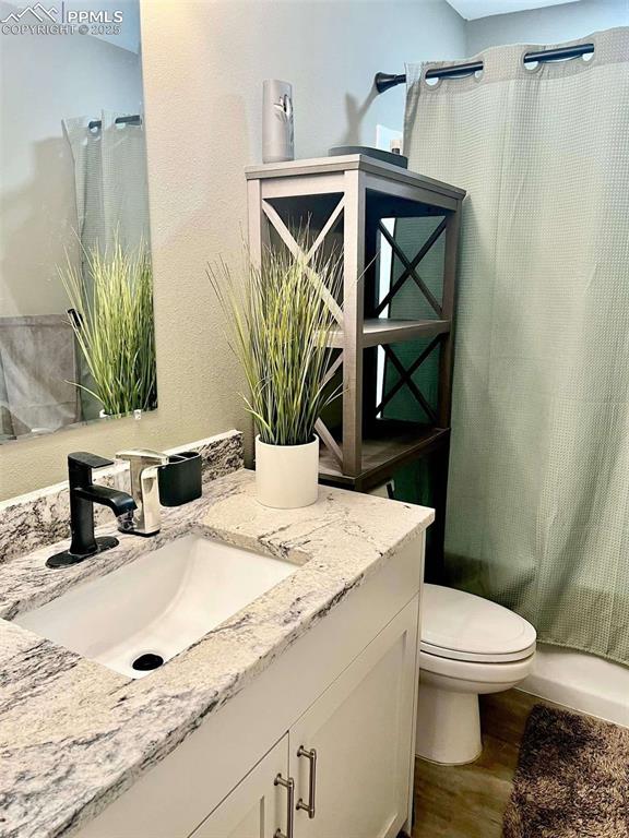 full bathroom with toilet, shower / bath combination with curtain, wood-type flooring, and vanity