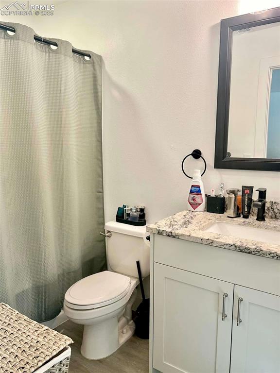 bathroom featuring toilet, hardwood / wood-style floors, vanity, and curtained shower