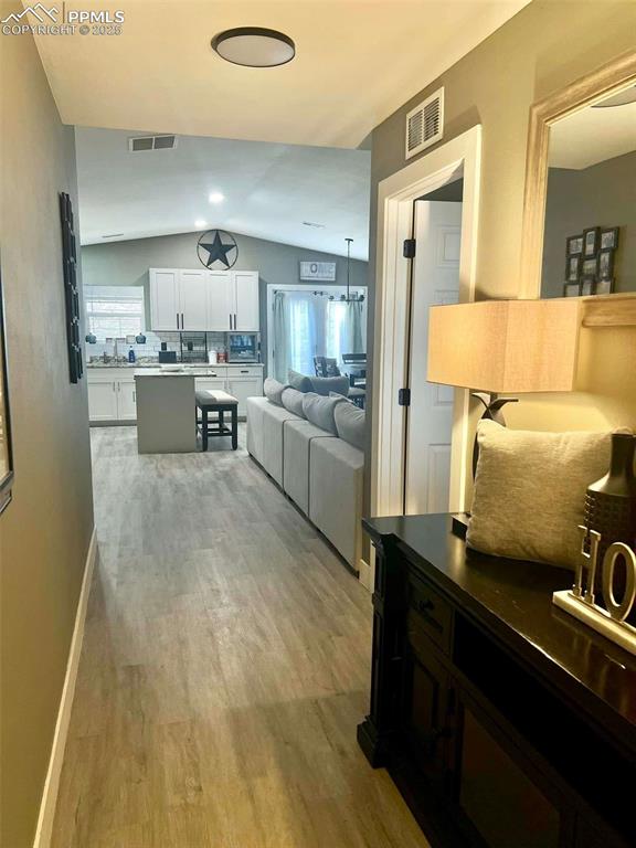 kitchen with light hardwood / wood-style floors, white cabinetry, decorative backsplash, and lofted ceiling