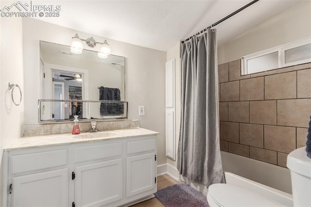 full bathroom featuring shower / tub combo with curtain, vanity, a textured ceiling, and toilet