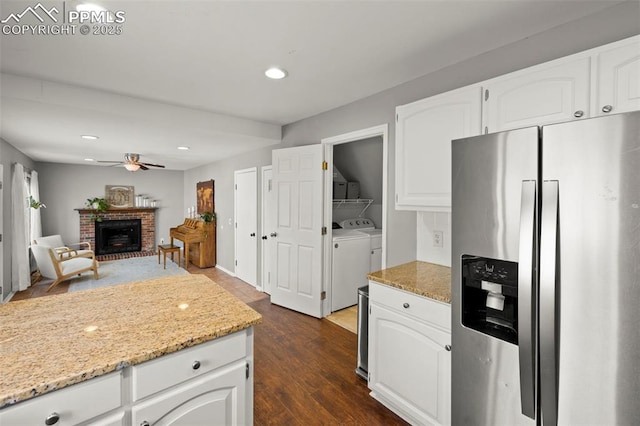 kitchen with stainless steel fridge with ice dispenser, light stone countertops, white cabinetry, and washer and dryer