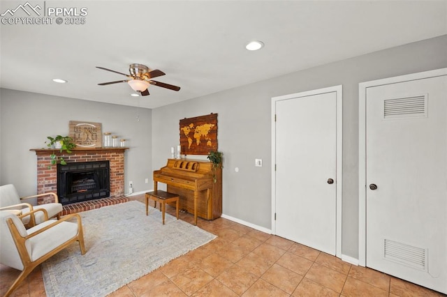 living area featuring ceiling fan, a fireplace, and light tile patterned flooring