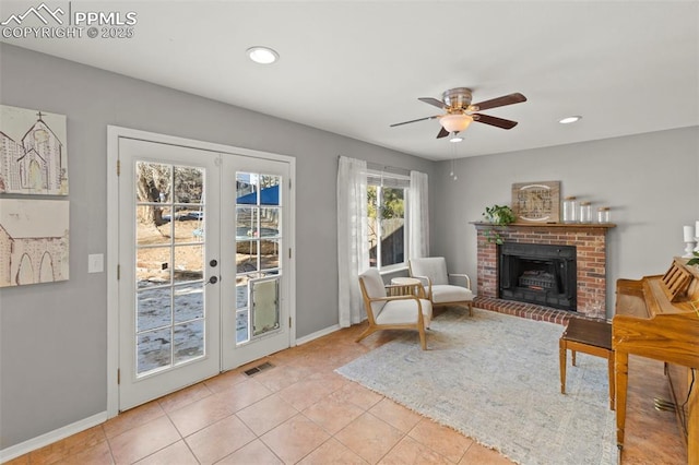 sitting room with a fireplace, ceiling fan, french doors, and light tile patterned flooring