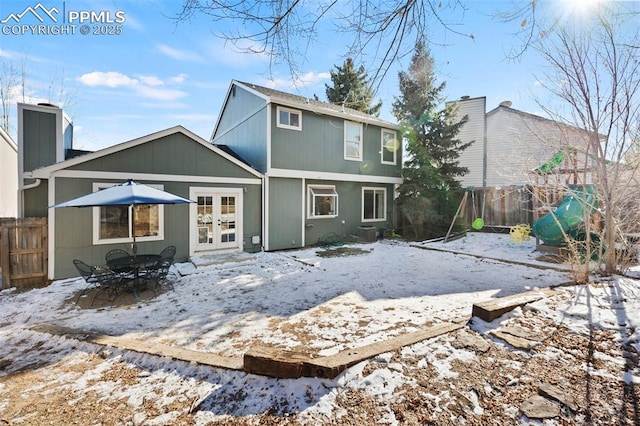 snow covered house featuring a playground, french doors, and central AC