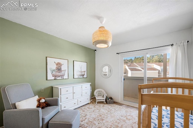 bedroom featuring a nursery area and a textured ceiling