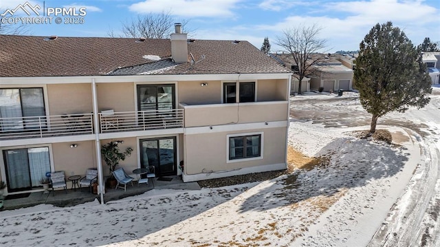 snow covered rear of property with a balcony