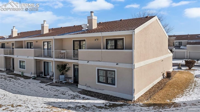 snow covered rear of property featuring a balcony