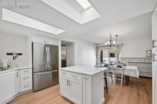 kitchen with white cabinetry, a skylight, and stainless steel refrigerator