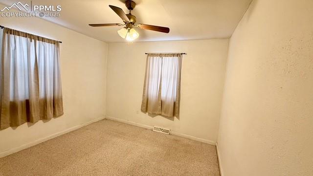 carpeted spare room featuring ceiling fan and plenty of natural light