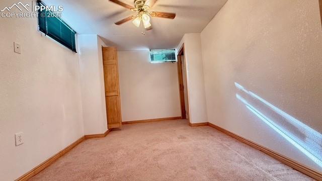 basement with ceiling fan and carpet