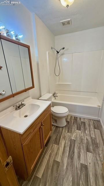 full bathroom with hardwood / wood-style flooring, toilet, vanity, and  shower combination