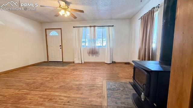 entrance foyer with ceiling fan, a wood stove, hardwood / wood-style floors, and a textured ceiling