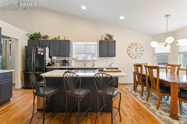 kitchen with black refrigerator, gray cabinets, a kitchen island, and backsplash