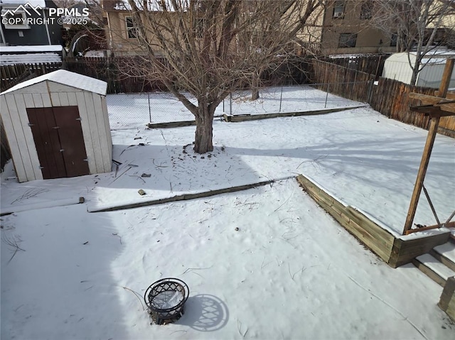 snowy yard featuring a fire pit and a shed