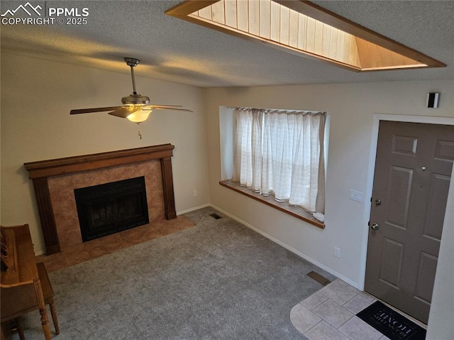 living room featuring ceiling fan, a textured ceiling, a fireplace, and light carpet