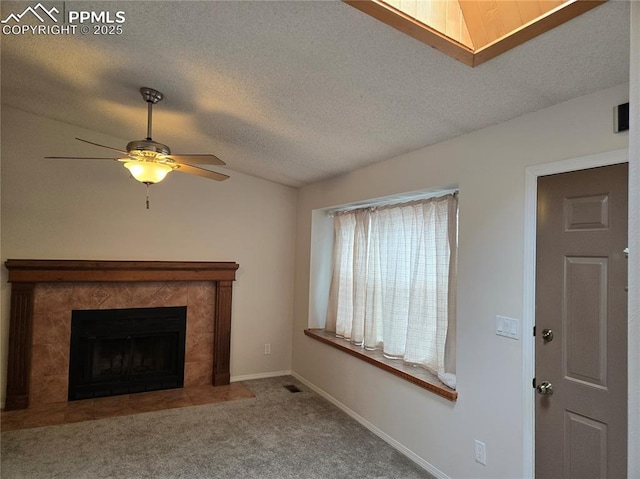 unfurnished living room featuring a textured ceiling, lofted ceiling, carpet floors, ceiling fan, and a tiled fireplace