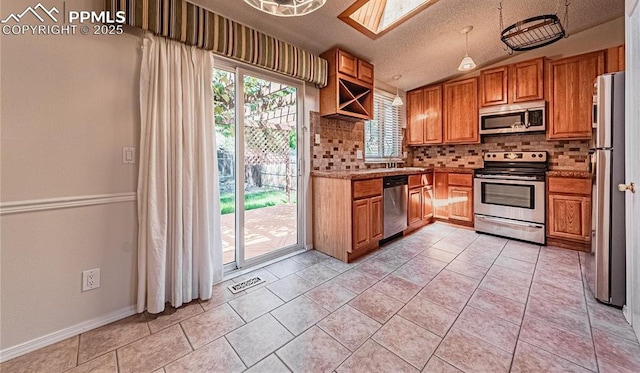 kitchen with a textured ceiling, stainless steel appliances, tasteful backsplash, light tile patterned flooring, and lofted ceiling with skylight