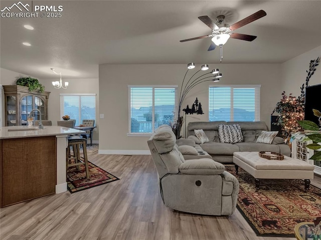 living room featuring sink, light hardwood / wood-style floors, and ceiling fan with notable chandelier