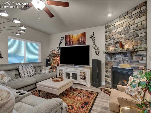 living room featuring light wood-type flooring, ceiling fan, and a fireplace