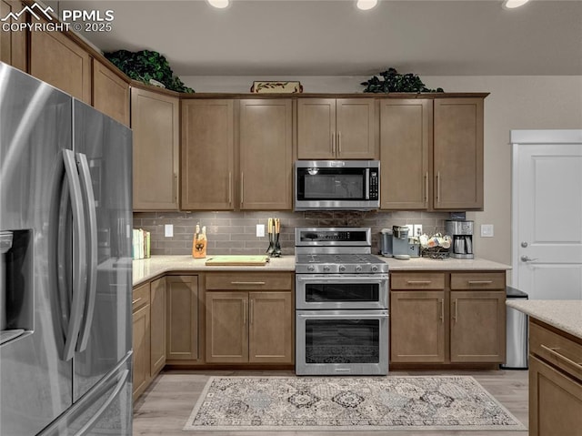 kitchen featuring light hardwood / wood-style floors, appliances with stainless steel finishes, and decorative backsplash