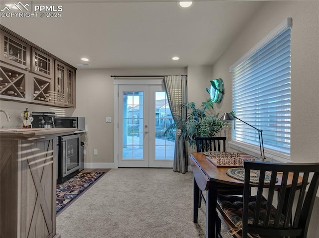 interior space featuring dark brown cabinets, french doors, plenty of natural light, light colored carpet, and beverage cooler