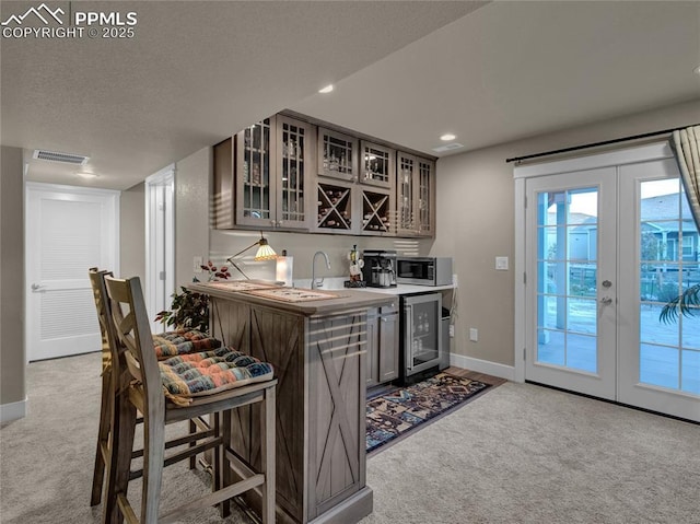 kitchen with sink, french doors, light colored carpet, and beverage cooler