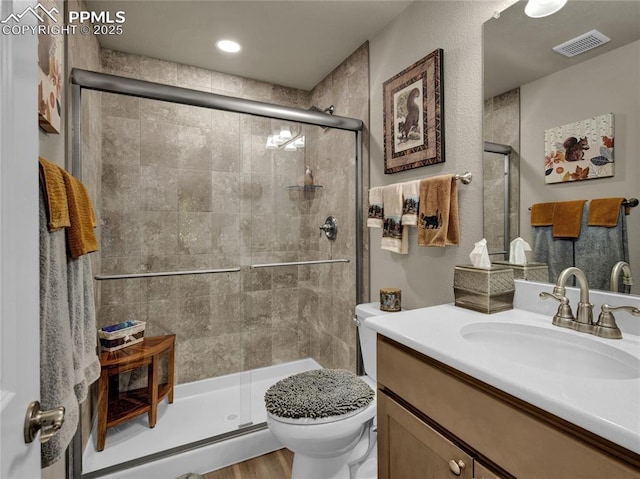 bathroom with vanity, toilet, an enclosed shower, and wood-type flooring