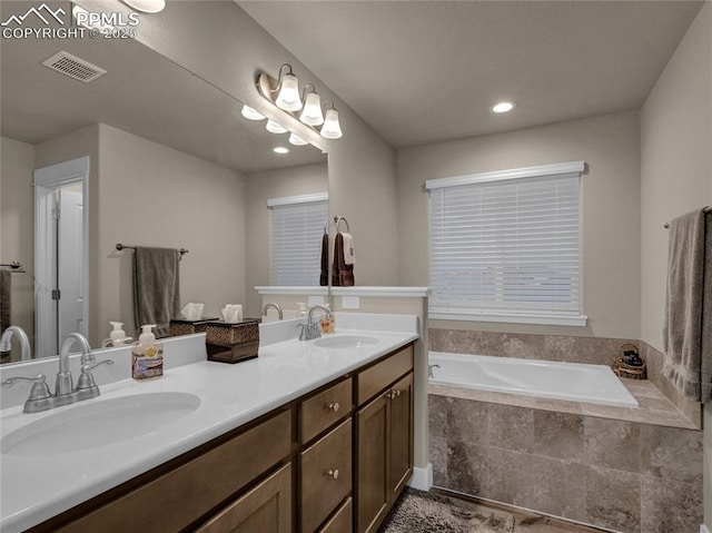 bathroom with tiled bath and vanity