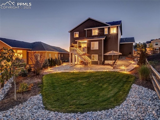 back house at dusk featuring a patio and a yard