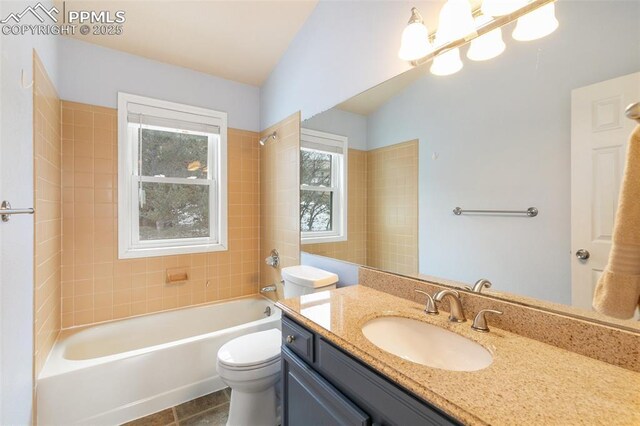 full bathroom featuring vanity, tiled shower / bath, and toilet