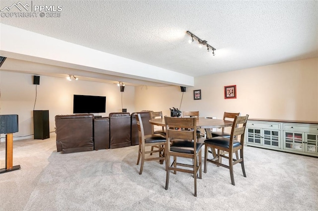 dining space with rail lighting, light carpet, and a textured ceiling