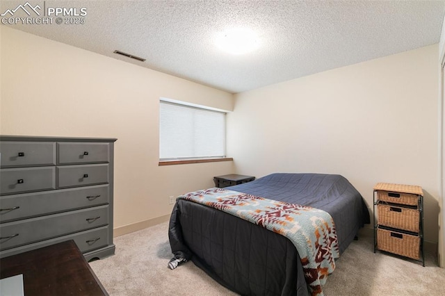 bedroom with light carpet and a textured ceiling