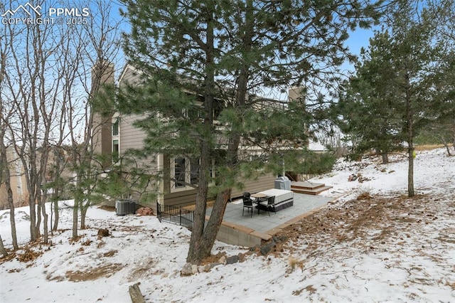 yard layered in snow with cooling unit and a wooden deck