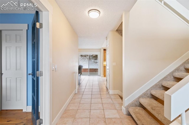 hallway featuring light tile patterned floors and a textured ceiling